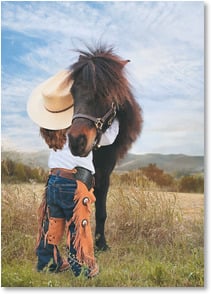 Photo of little cowgirl hugging pony