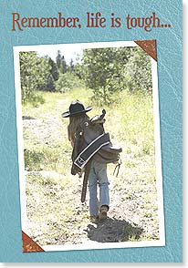 Young cowgirl walking with saddle