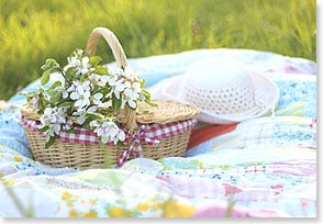 a spring hat sitting next to a picnic basket decorated with floral elements