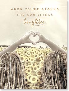 GIRLS MAKING HEART HANDS IN FRONT OF FIELD OF SUNFLOWERS