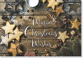 decorated sugar cookies surround the words warm Christmas wishes on a wooden table