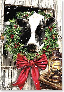 holstein cow with wreath around its neck in barn stall