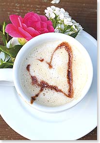 A latte in a coffee cup with a heart drawn in the foam